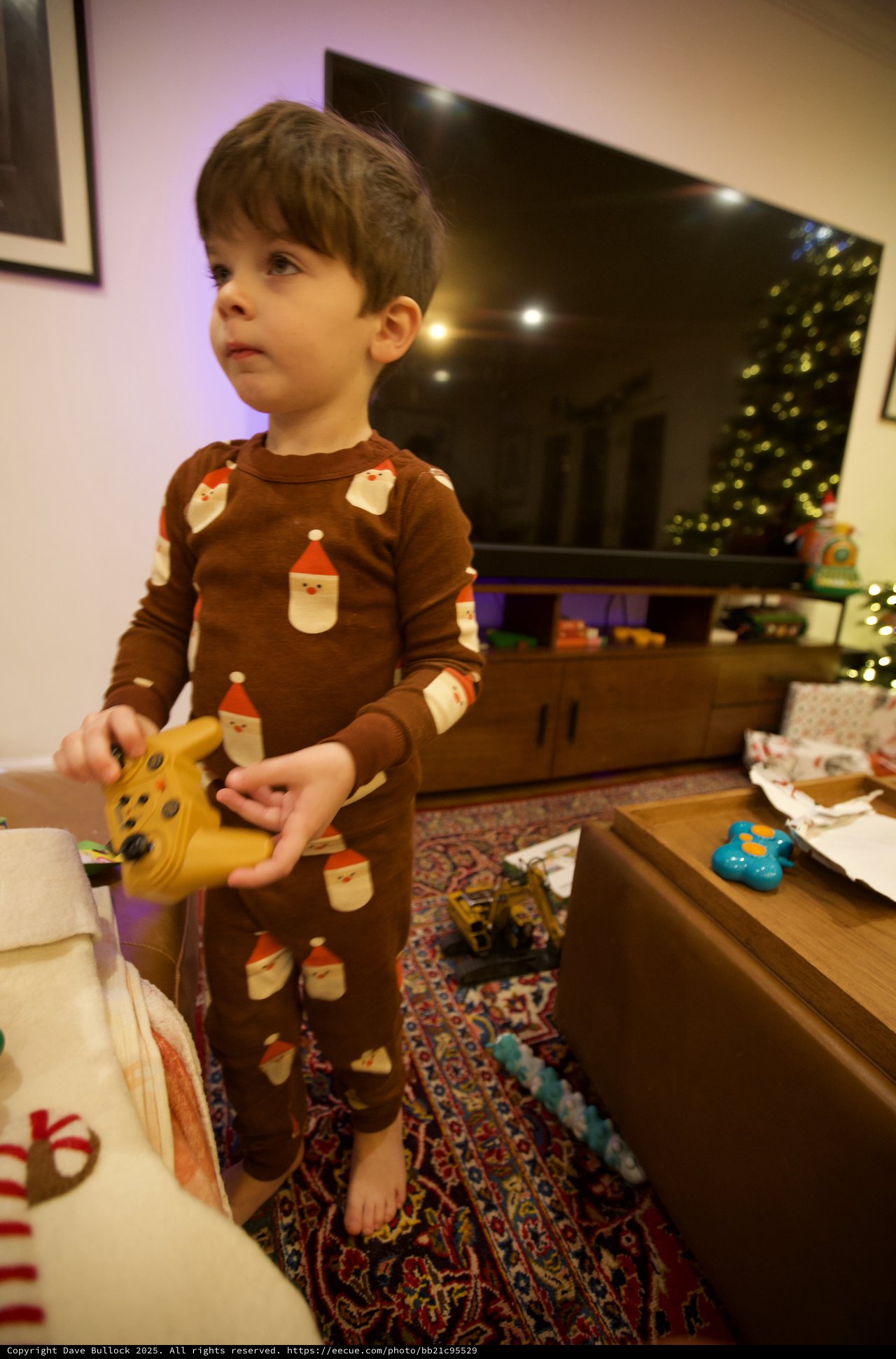 Young Child Opening Christmas Presents in Brown Santa Pajamas