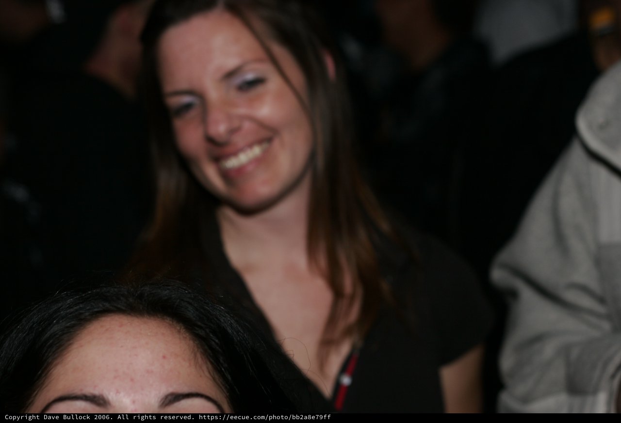 Woman Smiling Joyfully at Crowded Nighttime Event