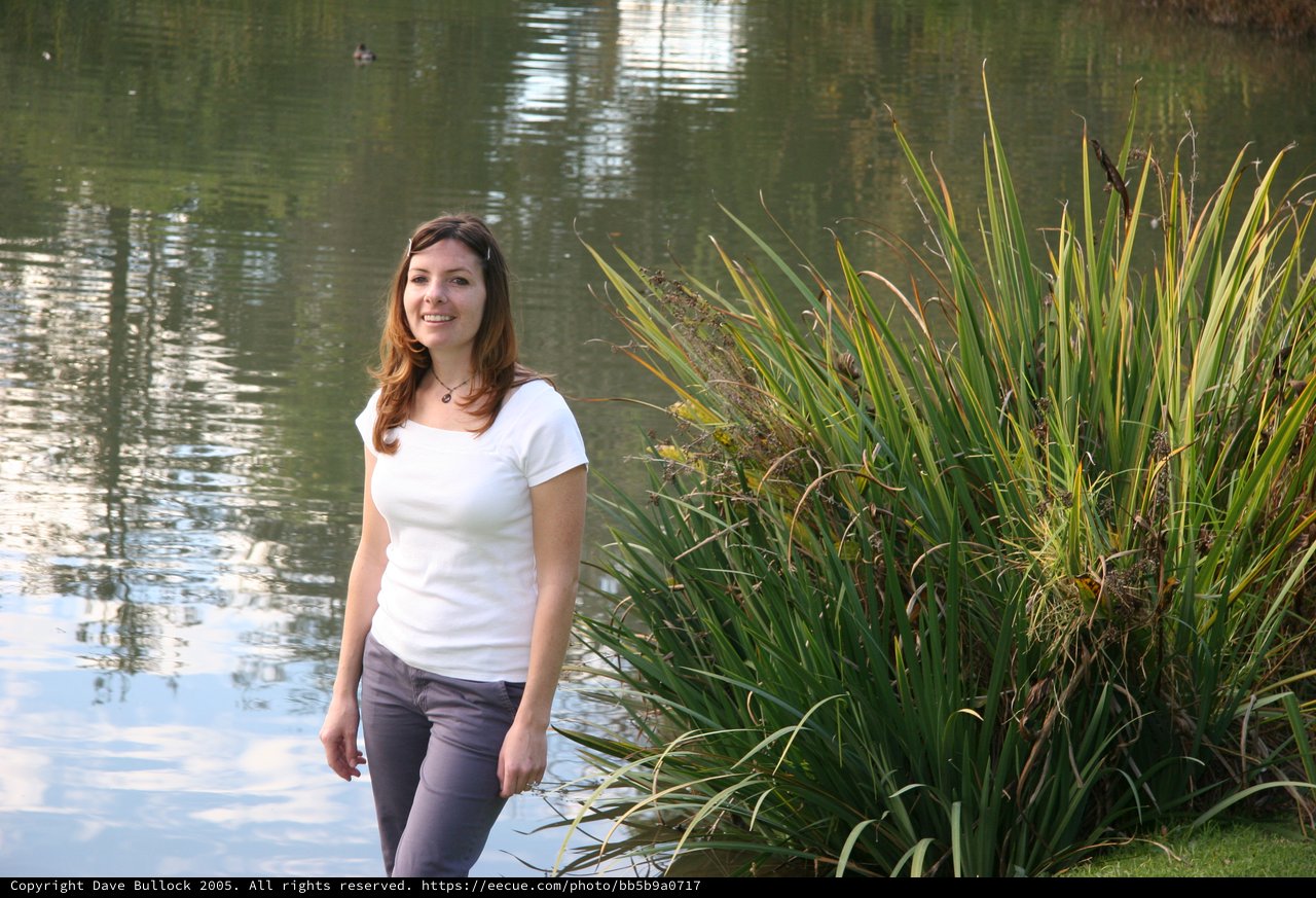 Young Woman Smiling by a Tranquil Park Pond