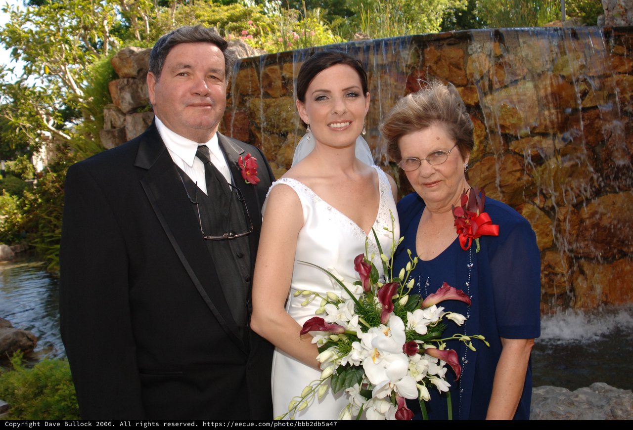 Bride Poses with Parents at Waterfall Wedding Venue