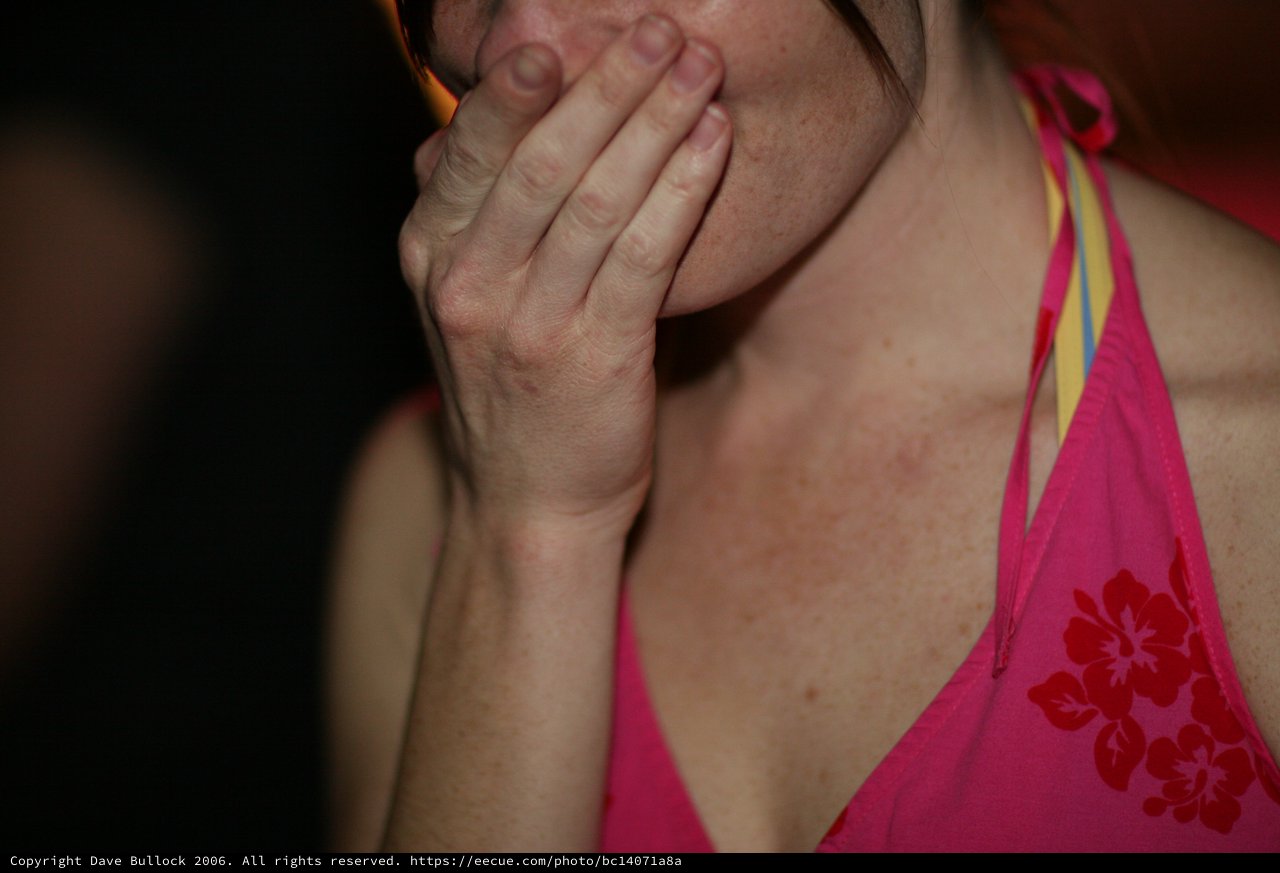 Woman Covers Mouth in Surprise at Event