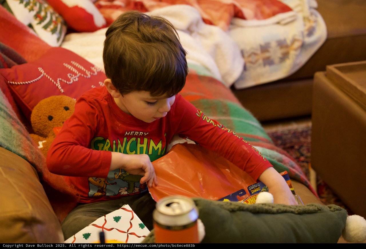 Young Boy Opening Christmas Presents in Red Grinch Pajamas