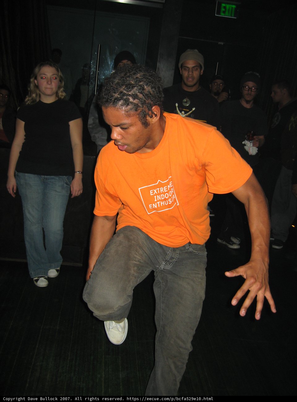 Orange Shirt Man at the Sunday Club Caption: This man in an orange shirt is ready to dance the night away at the Sunday Club with his jeans and shoes.