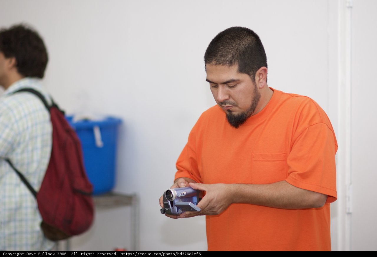 Man in Orange Shirt Texting on His Phone