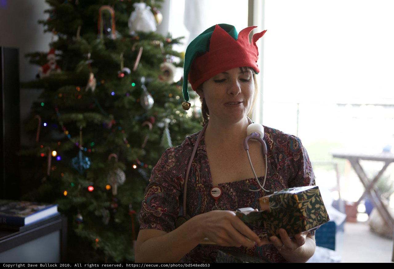 Holiday Elf Nurse Unwrapping Christmas Gift at Home