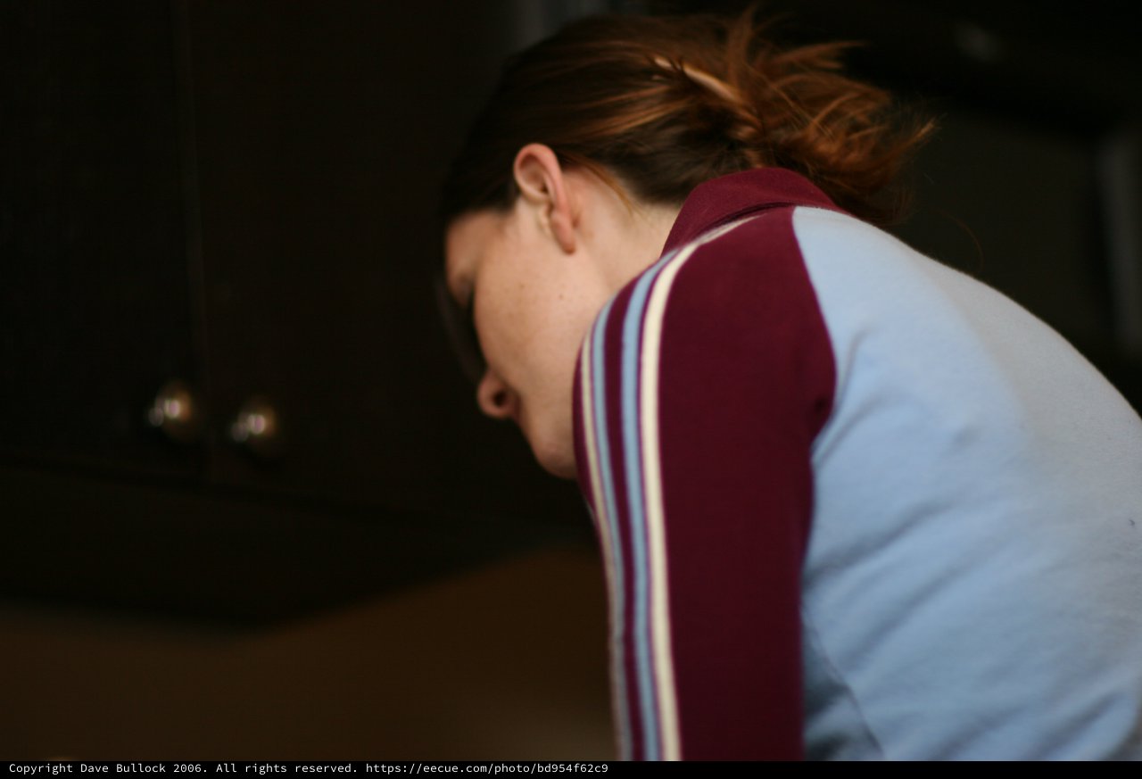 Woman in Varsity Jacket Bending Forward Indoors