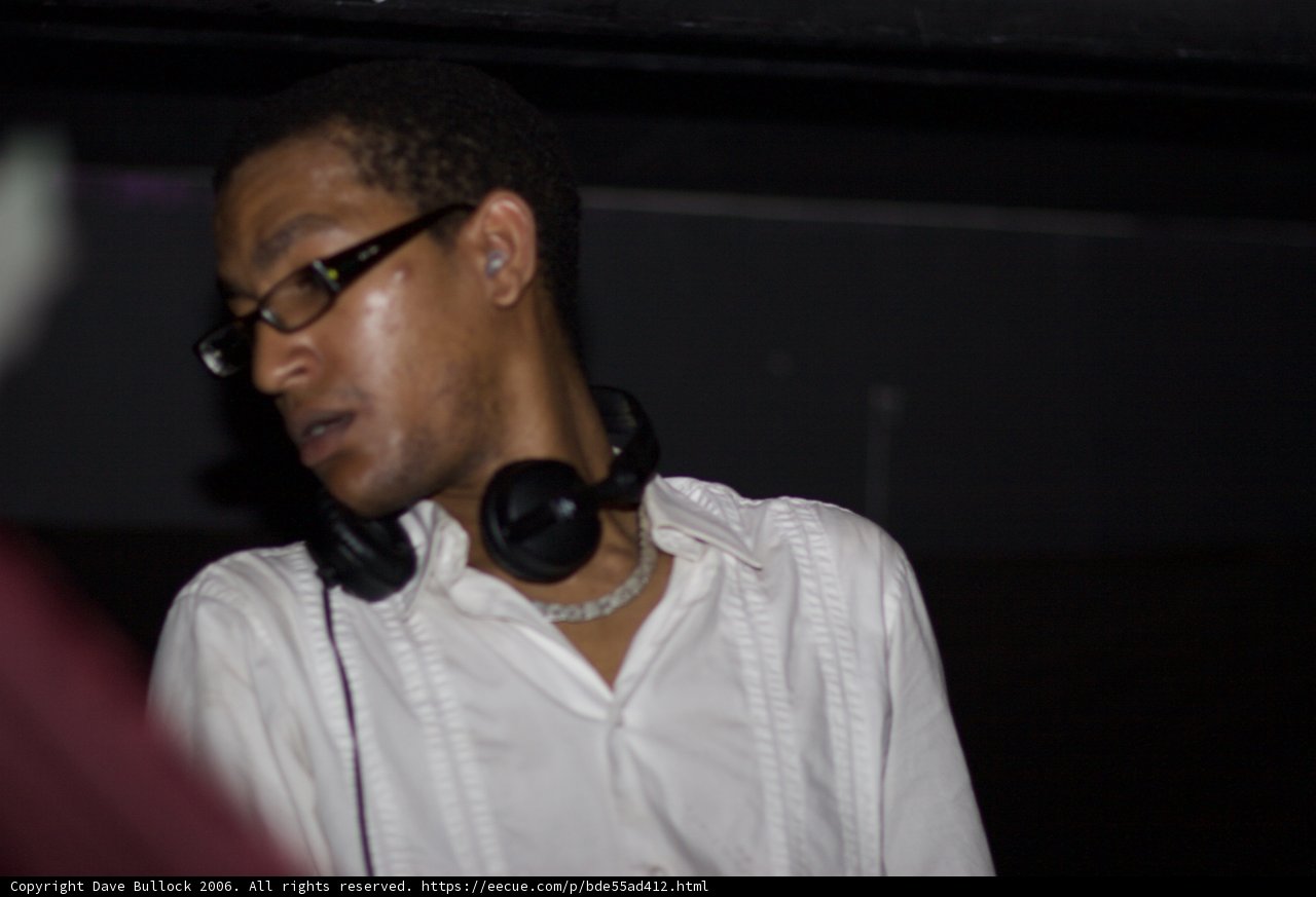 Man in White Shirt Listening to Music with Headphones