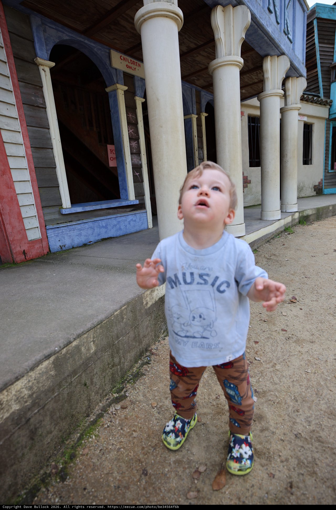 Young Child Looking Up in Wonder at Vintage Storefront