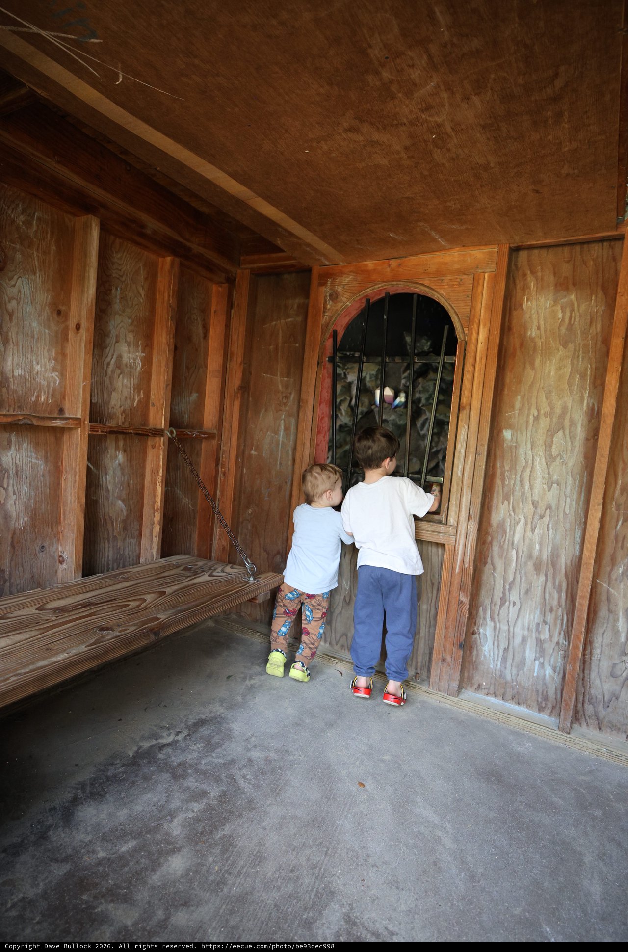 Two Children Peering Through Barred Window at Fantasyland