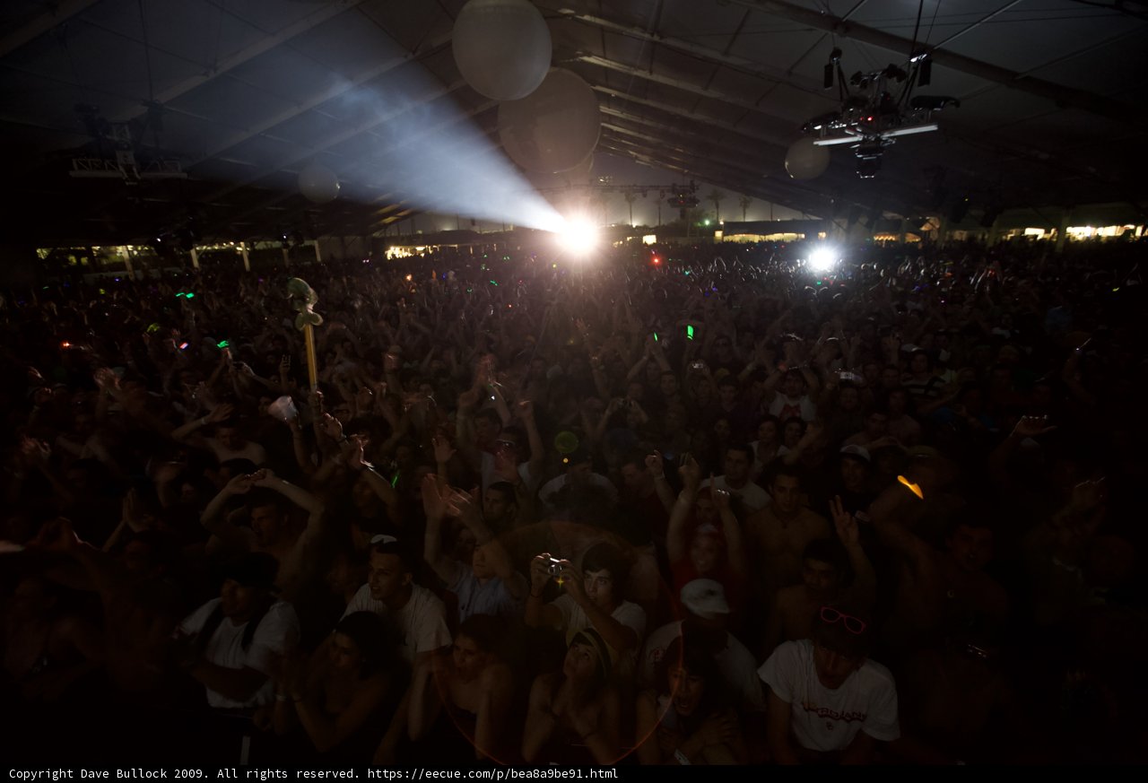 Lights, Crowd, Action Caption: The energy at Coachella '09 was electric as the audience cheered and swayed to the beat, illuminated by dazzling spotlights and colorful flares.