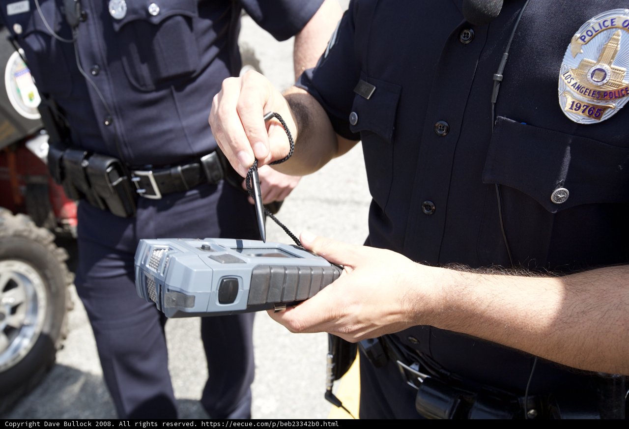 Police Officer Examining Car with High-Tech Device