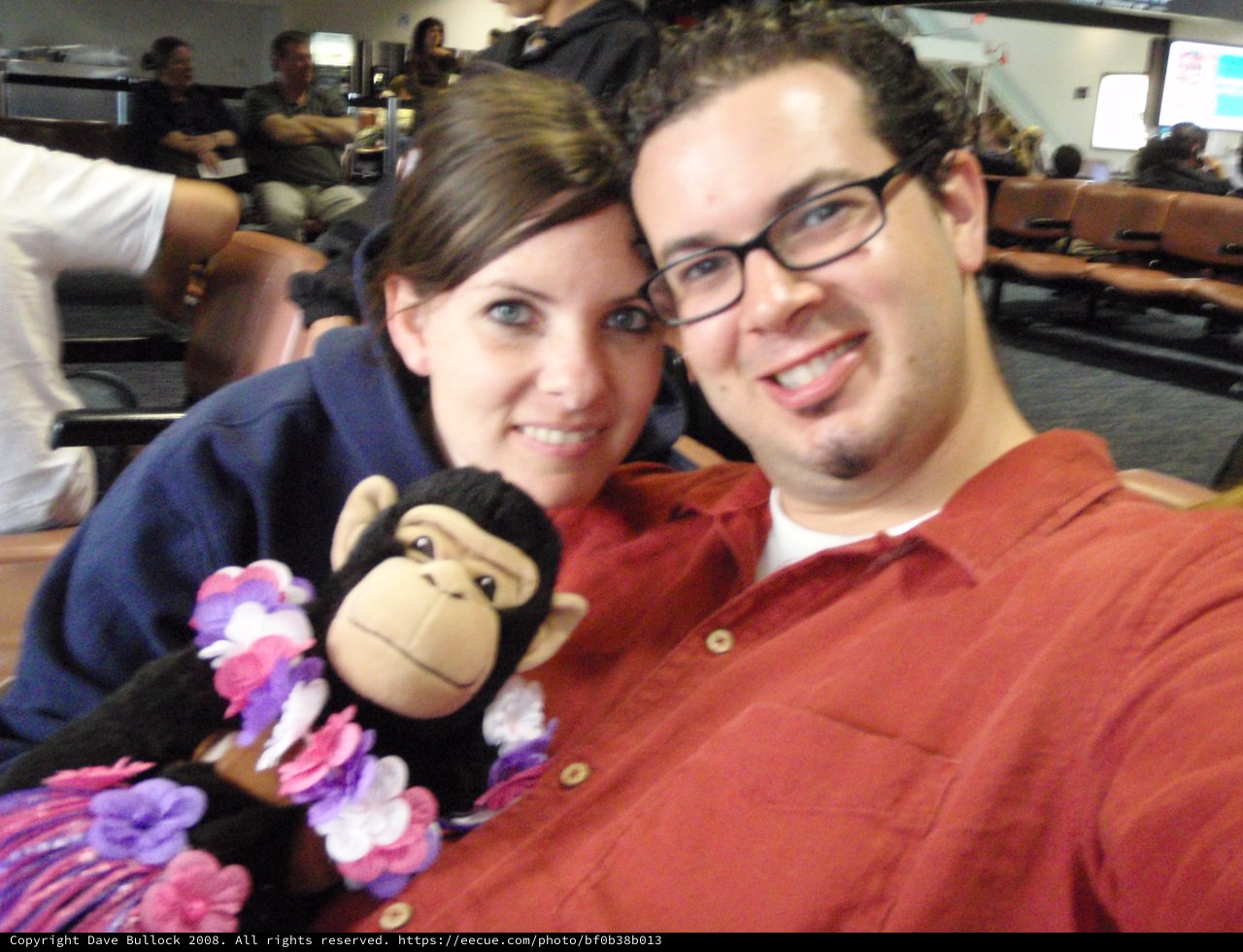 Couple Poses with Monkey Plush at Airport Gate