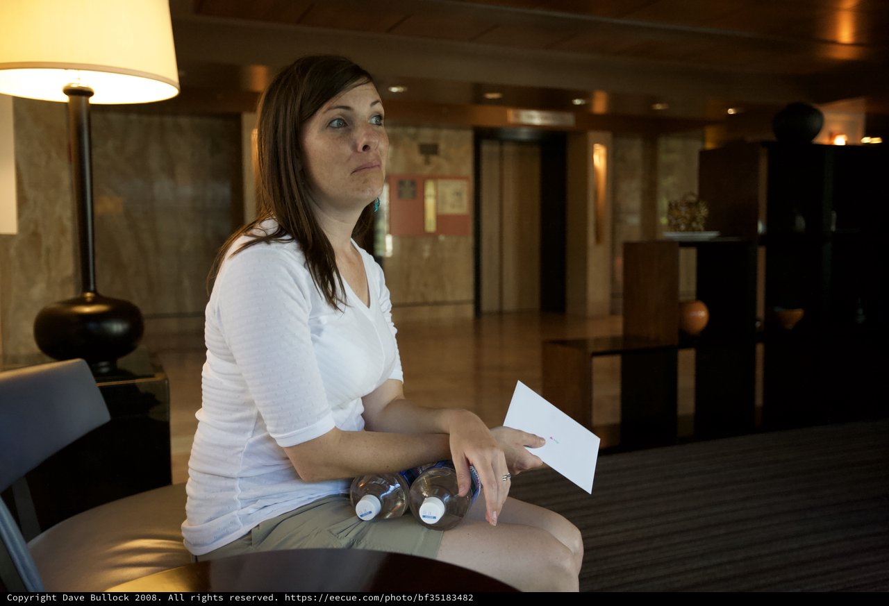 Woman Waiting in Hotel Lobby with Water Bottles