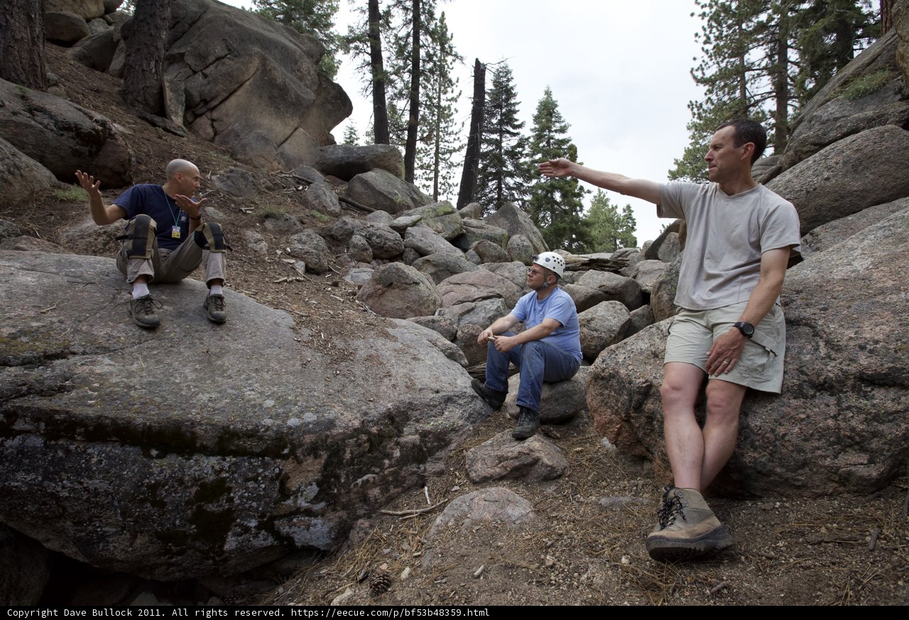Three Men Resting on Rocks in the Wilderness
