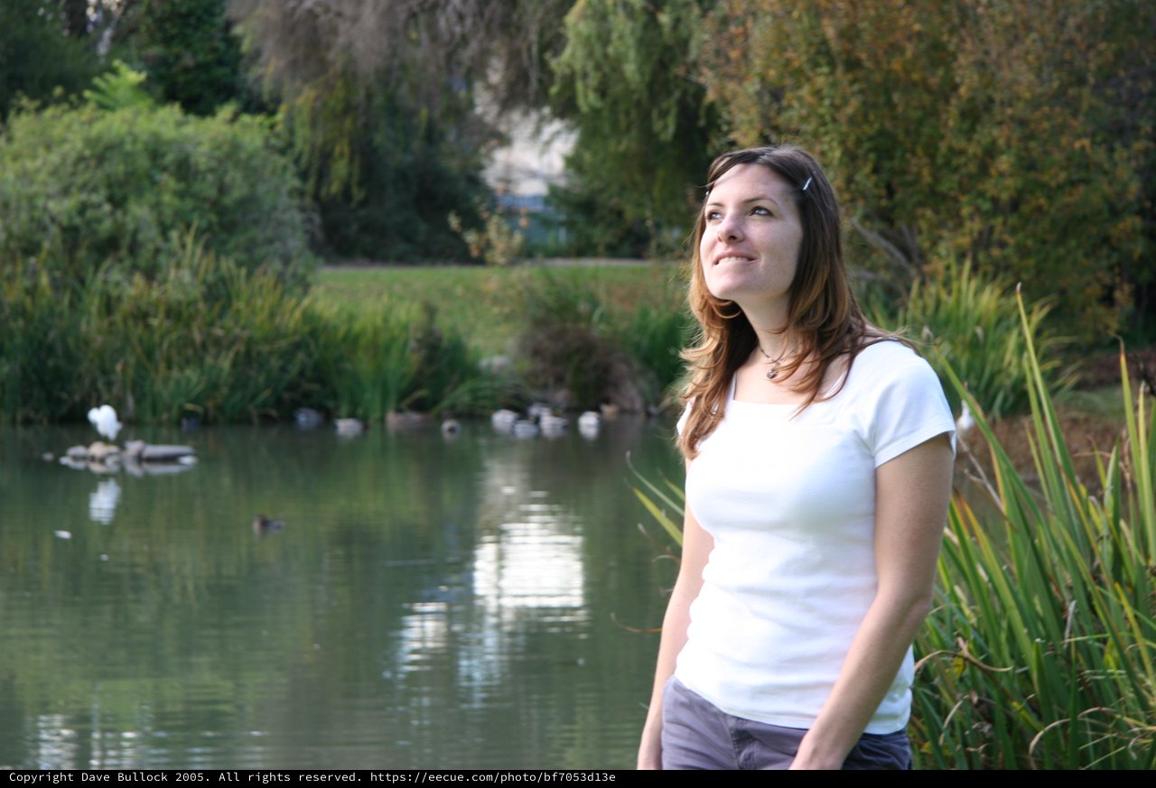 Young Woman Smiling by a Tranquil Park Pond