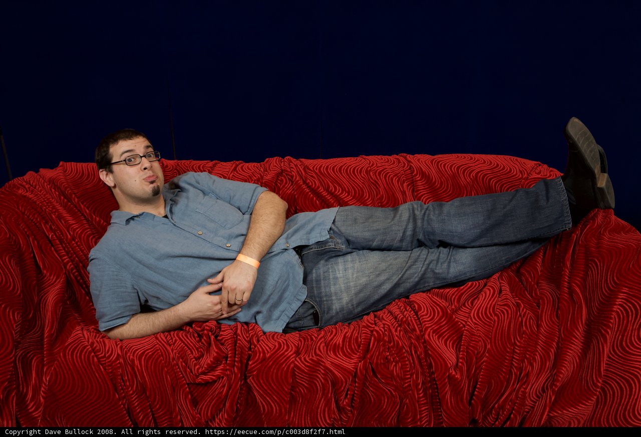 Man lounging on red velvet couch