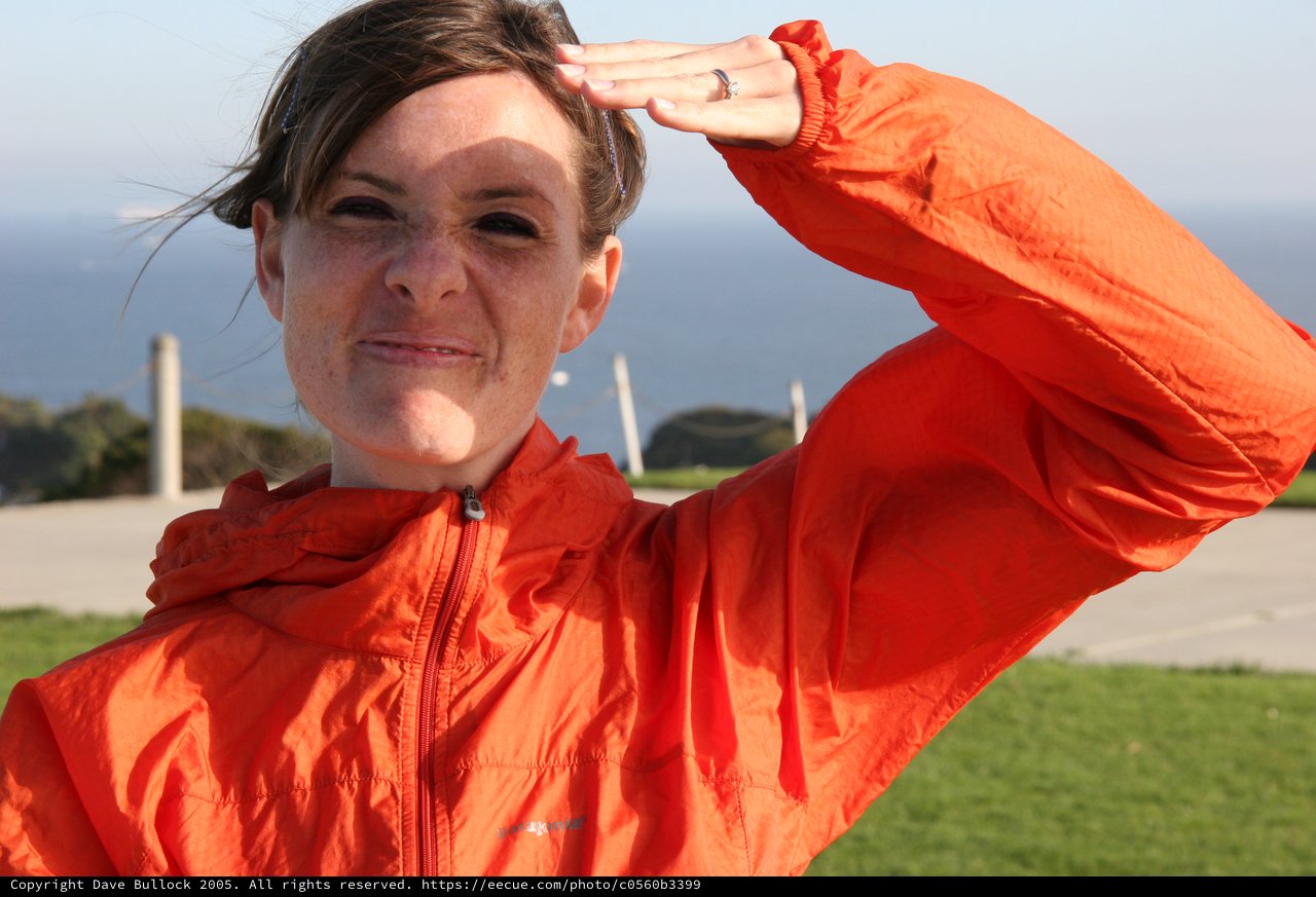 Woman in Orange Jacket Saluting by the Coast