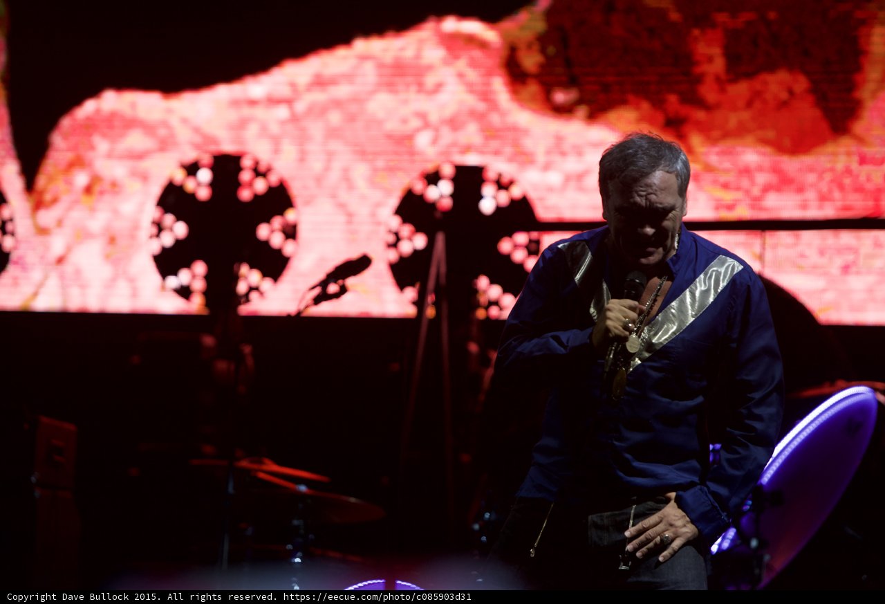 Morrissey Looking Down Dramatically Blue Shirt Mic Stand Two Circular Lights Drums LED Head Red Screen
