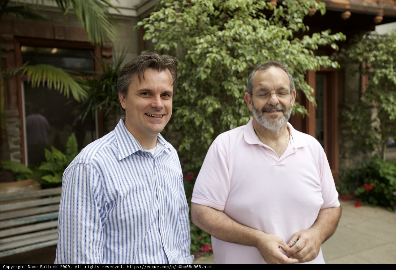 Two Men Enjoying the Outdoors in Front of a House