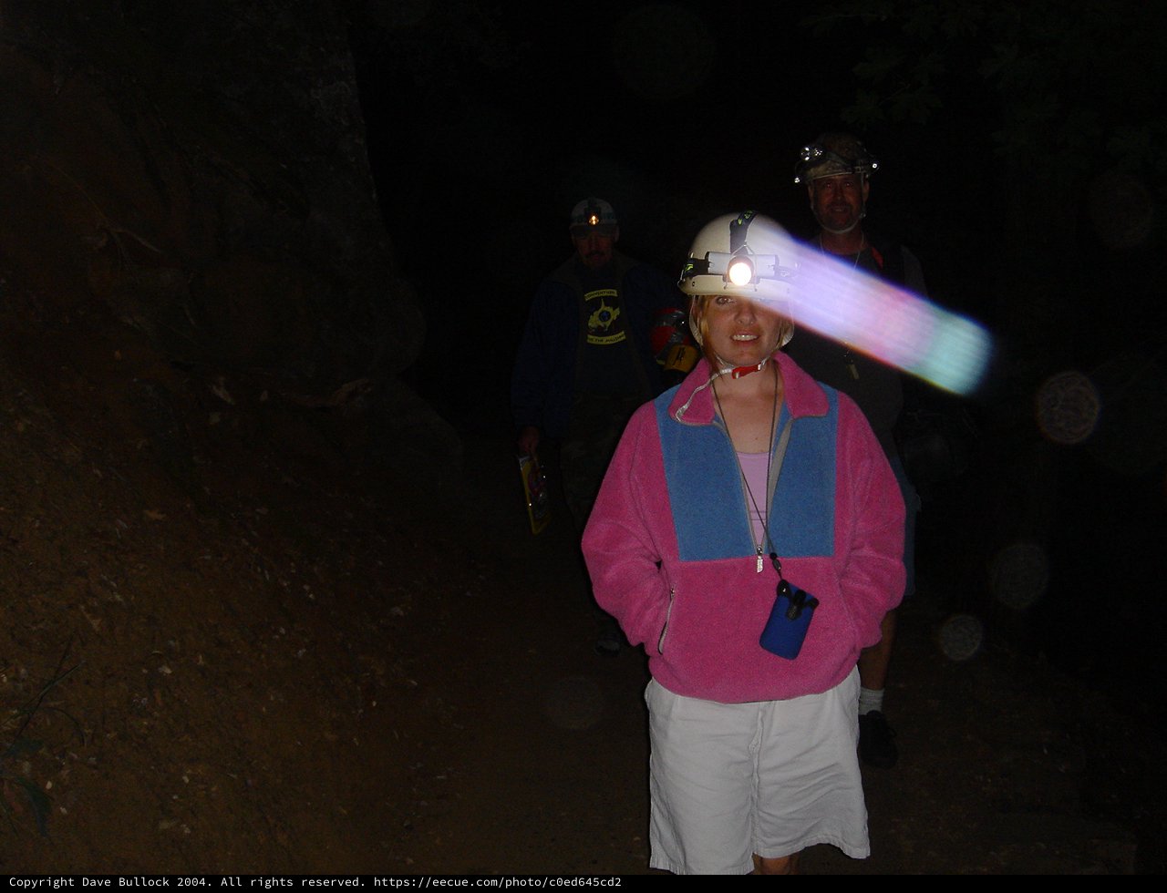 Cave Explorers with Headlamps in Dark Tunnel