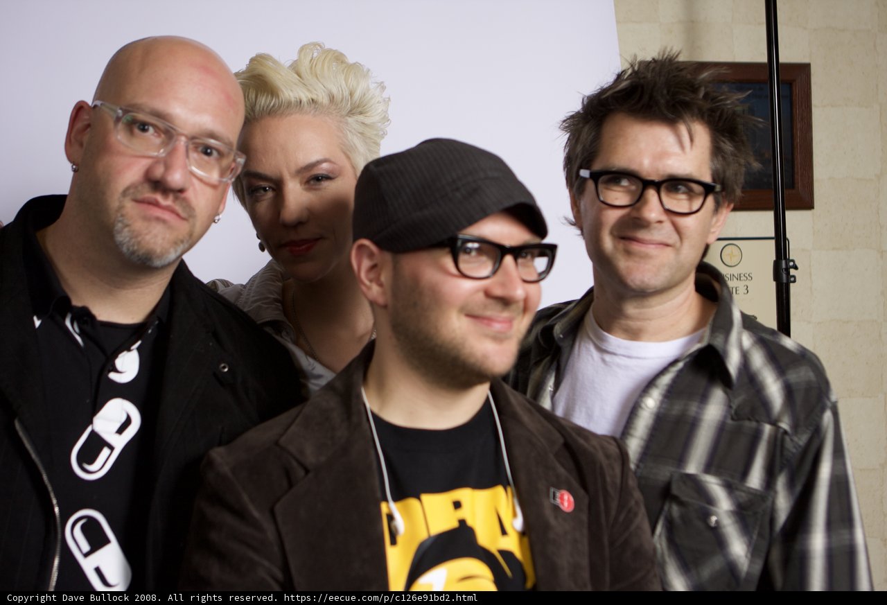 Four Men Standing Together, One Wearing Glasses