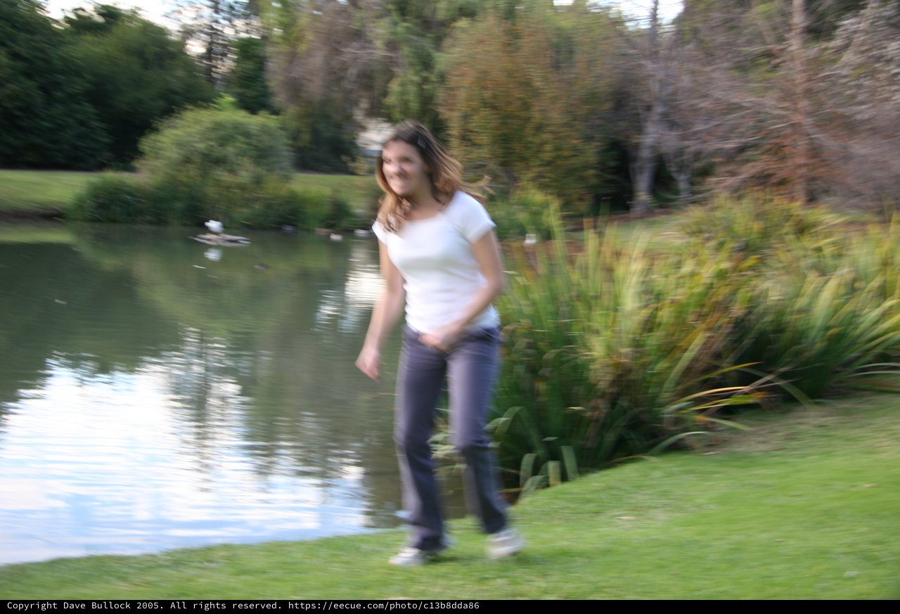 Young Woman Walking Beside a Tranquil Pond