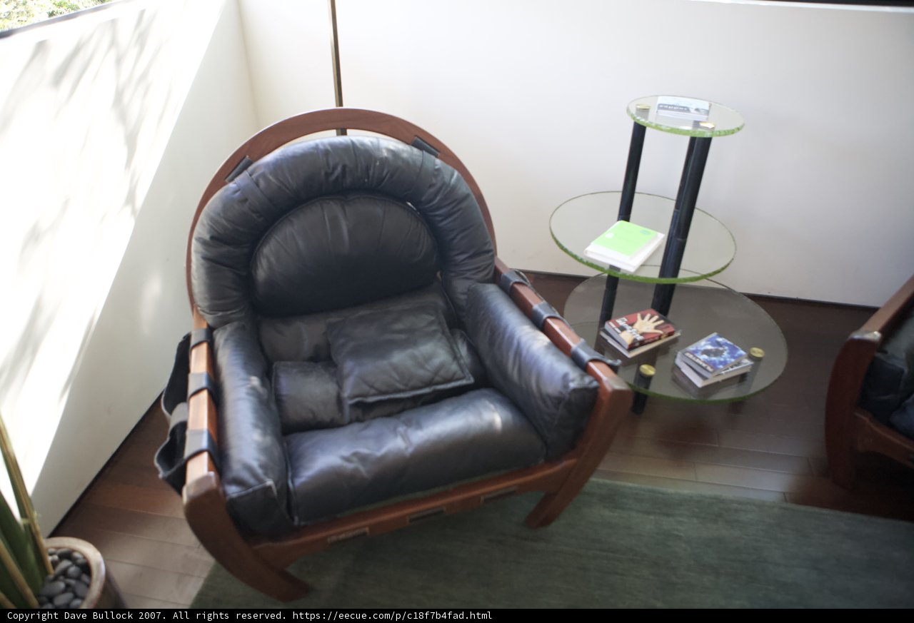 Sleek leather armchair with green cushion
