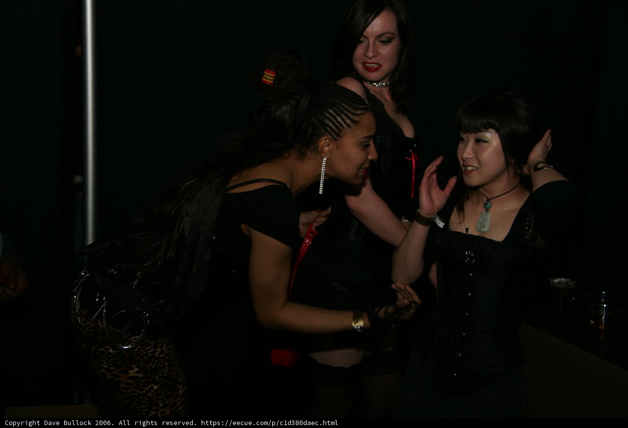 Three women in black corsets and stockings dancing at a night club
