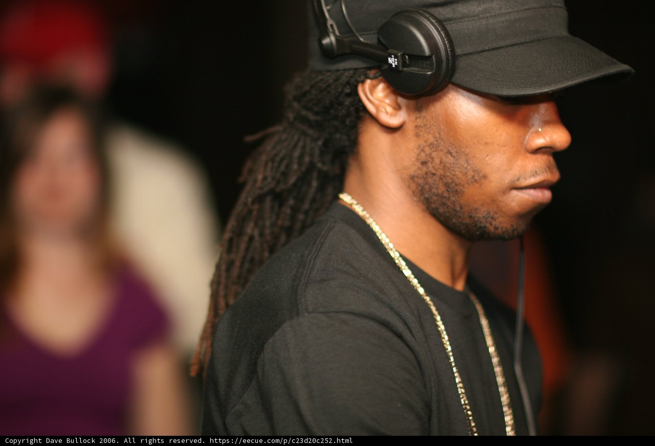 The Man in the Black Hat Caption: An enigmatic figure stands alone, sporting a black baseball hat and sleek sunglasses, in this stunning snapshot from 2006.