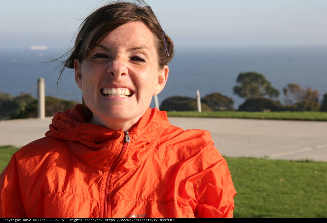 Joyful Woman in Orange Jacket by the Sea