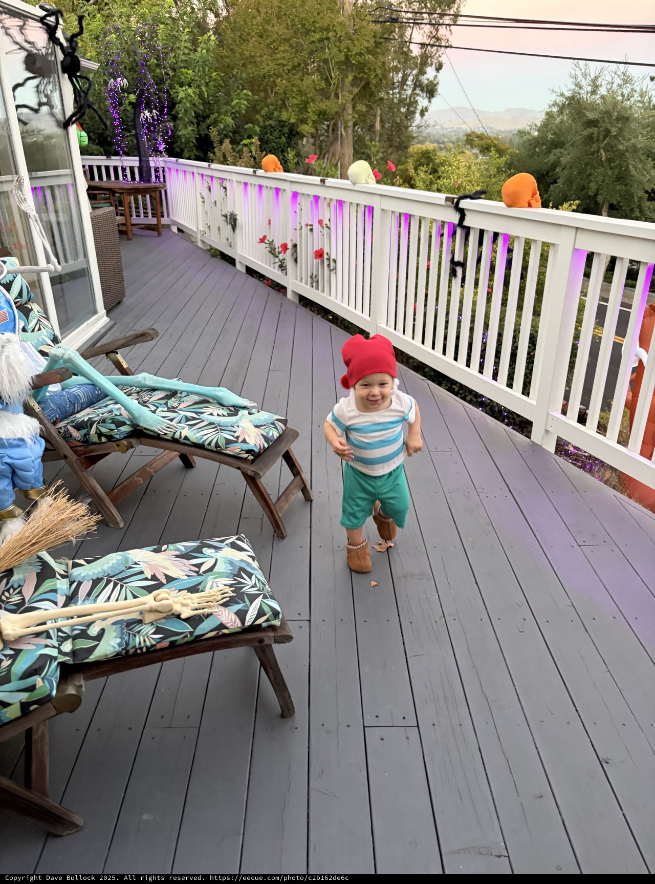 Joyful Toddler in Pink Hat Running on Decorated Deck