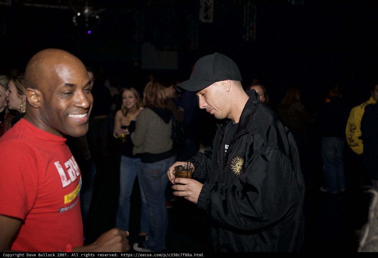 Man in Red Shirt and Black Hat Sips Drink at Funky Funktion Party