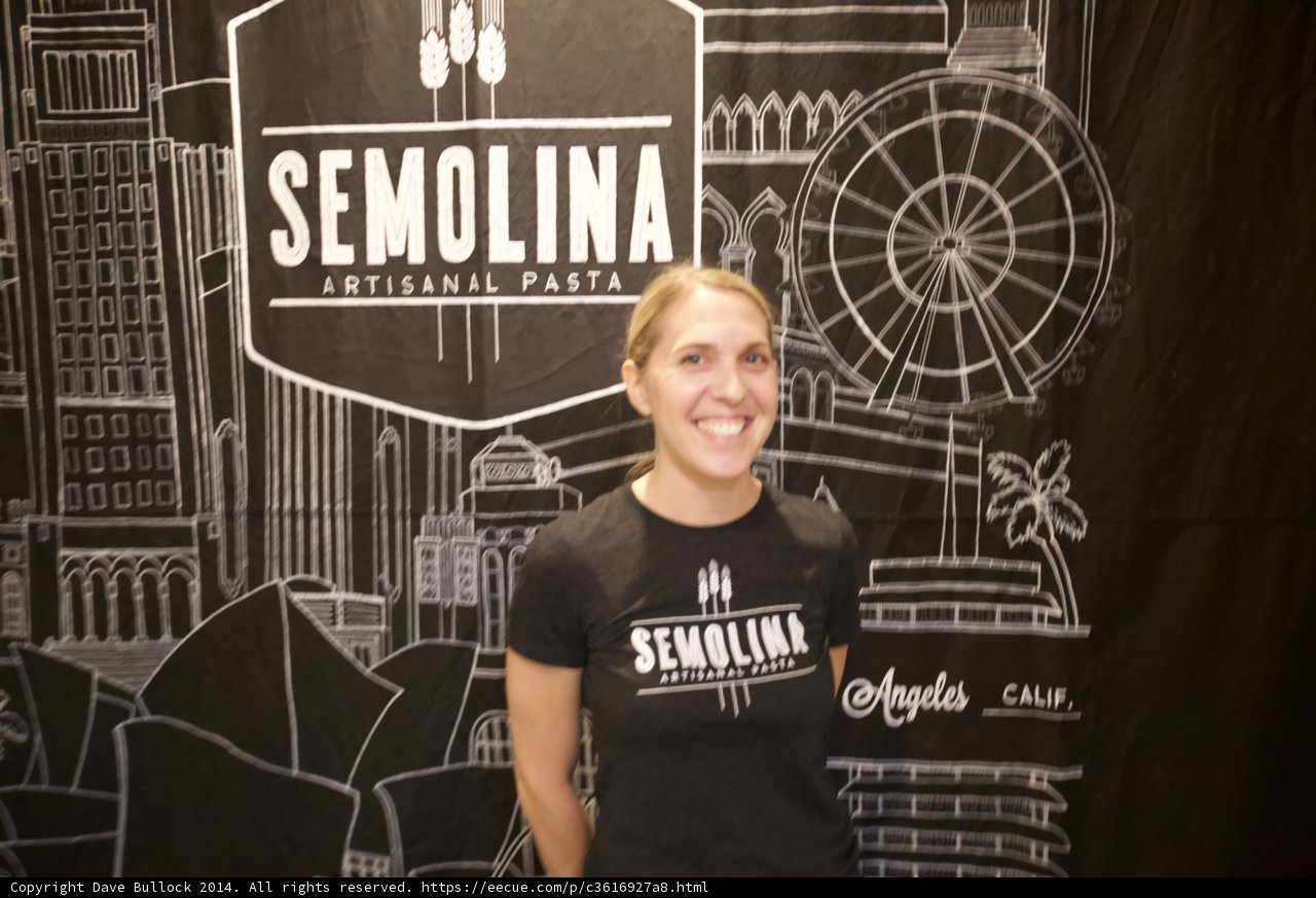 Smiling Woman Poses in Front of Semolina Sign