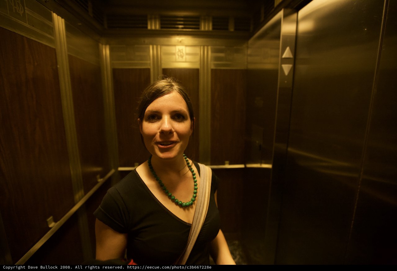 Woman Smiling in Vintage Wood-Paneled Elevator