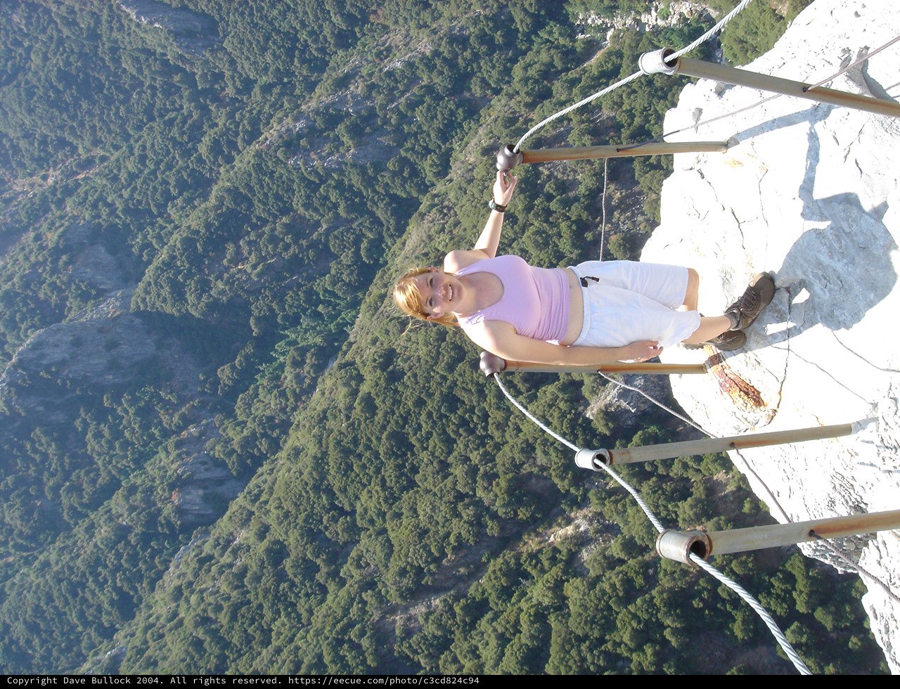 Fearless Woman Perches on Cliff Edge Over Mountain Abyss