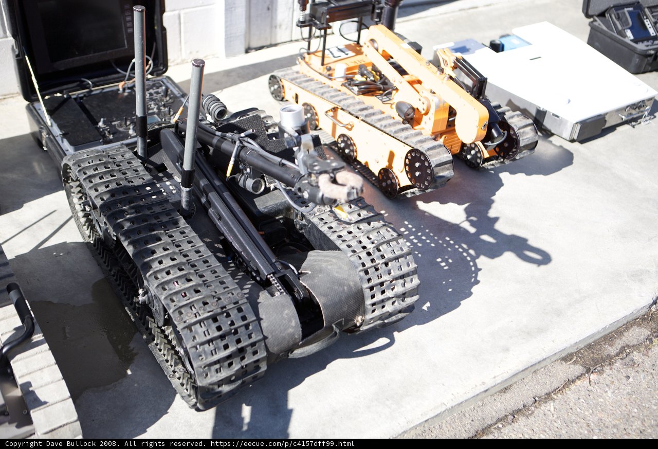 Machine Robot Among Military Equipment
