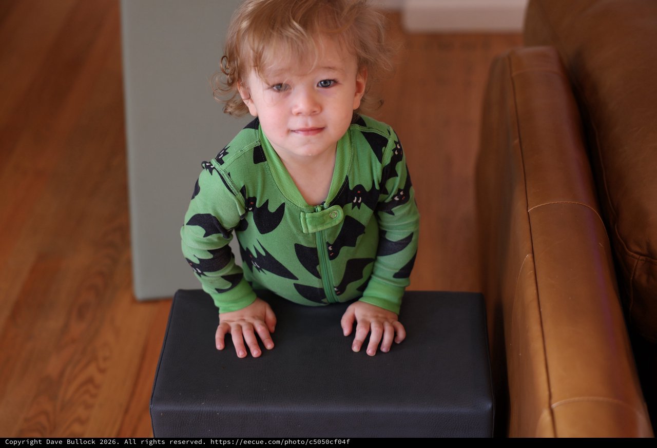 Toddler in Green Bat Pajamas on Ottoman