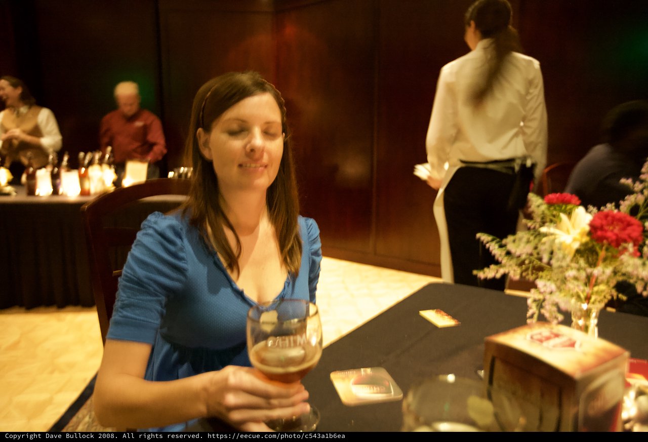 Woman Smiling Over Craft Beer at Evening Event