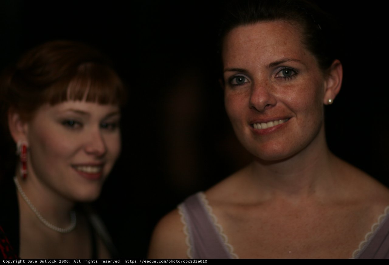 Two Women Smiling at a Dimly Lit Evening Event