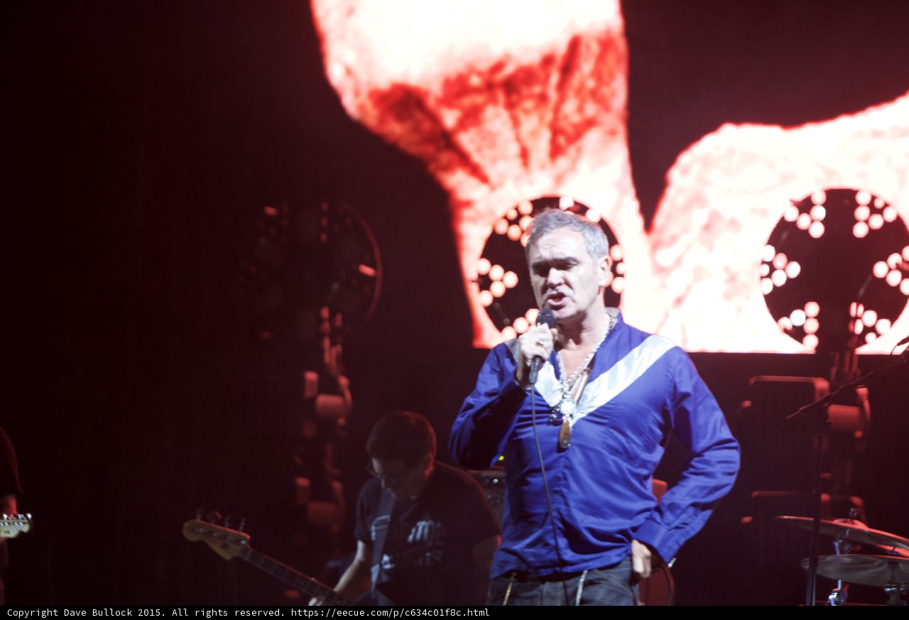 Morrissey Singing Blue Shirt Hand On Hip Bassist Background Red Video Screen Abstract Imagery