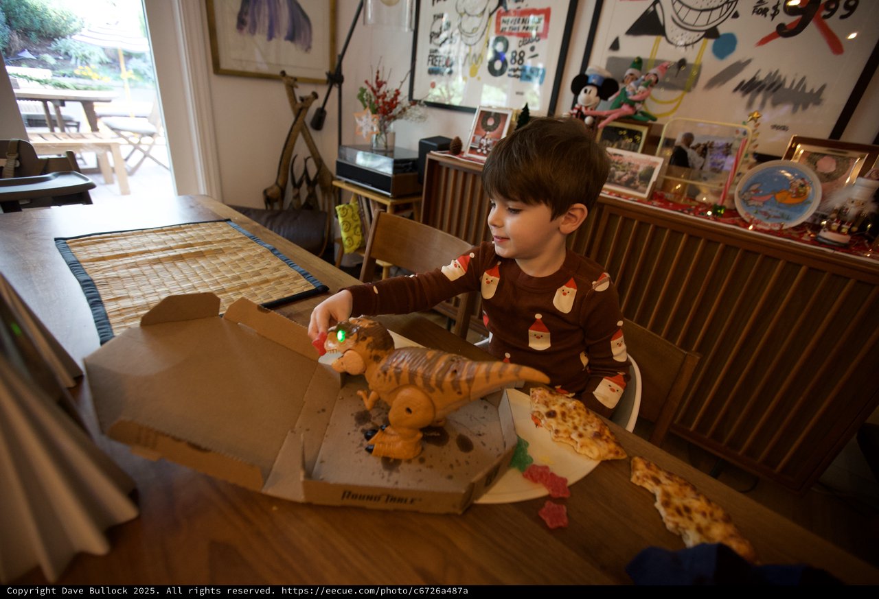 Child Enjoying Pizza with Dinosaur Toy on Christmas