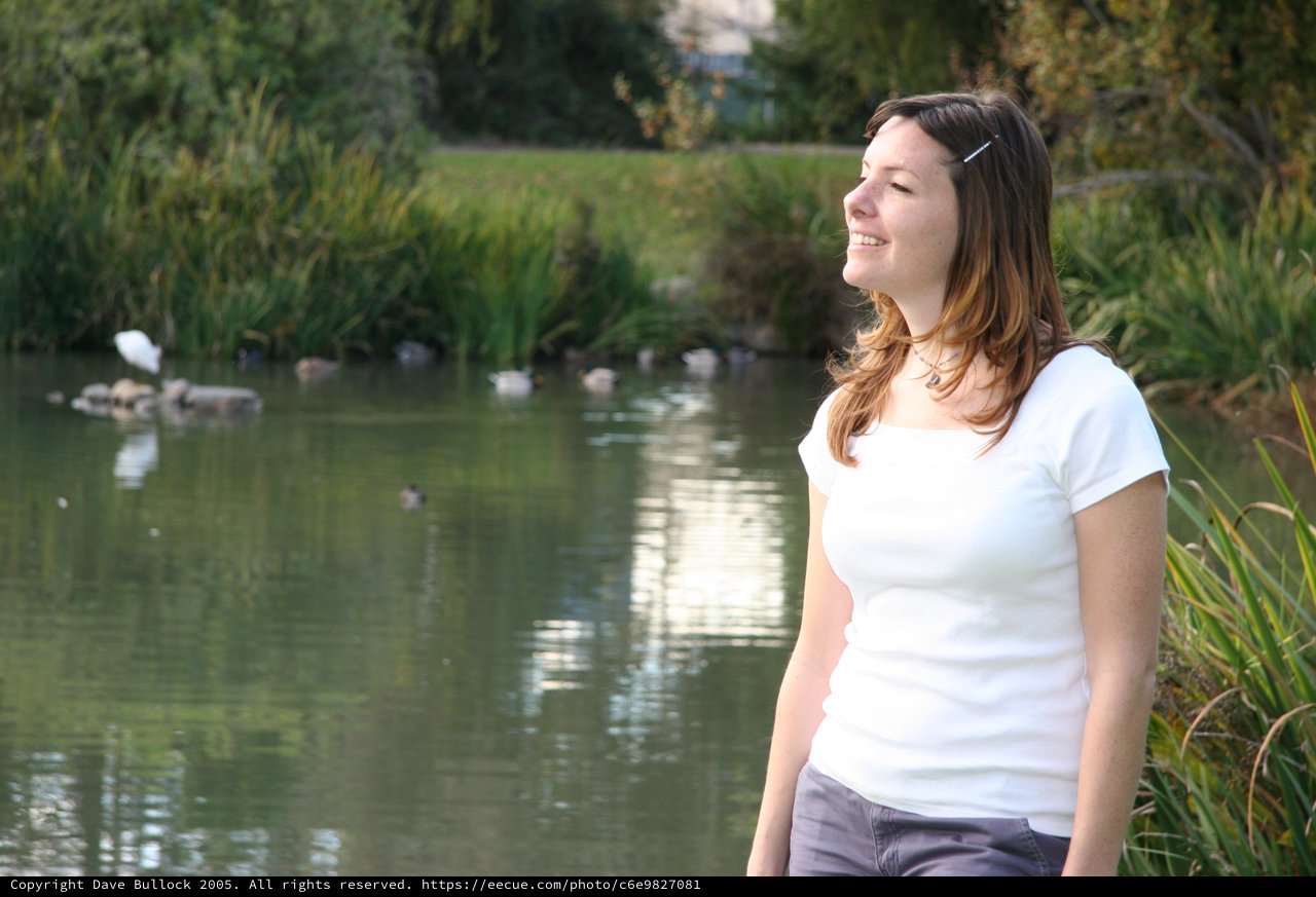 Joyful Woman Smiling by a Tranquil Park Pond