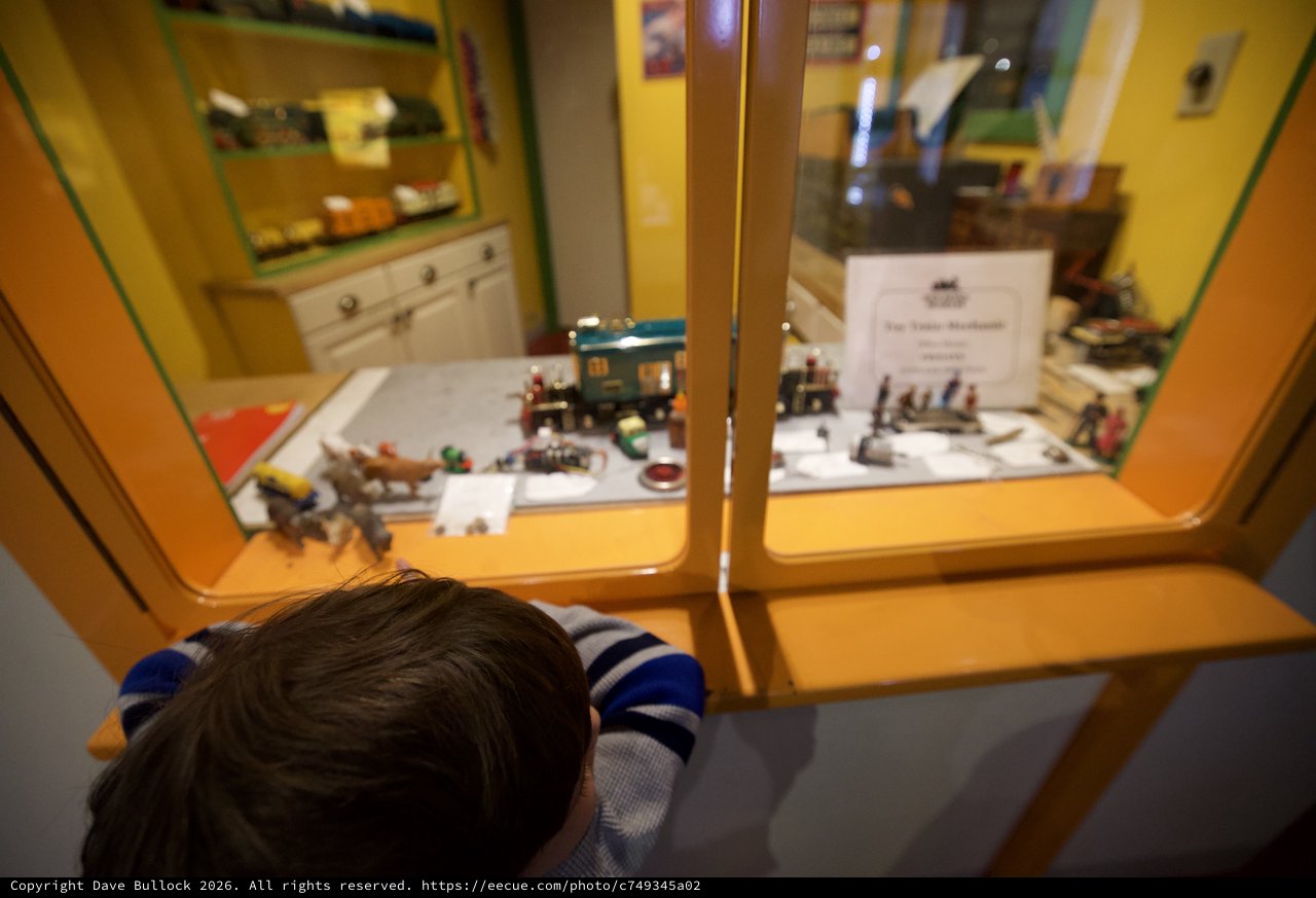 Child Examining Miniature Train Display at Museum
