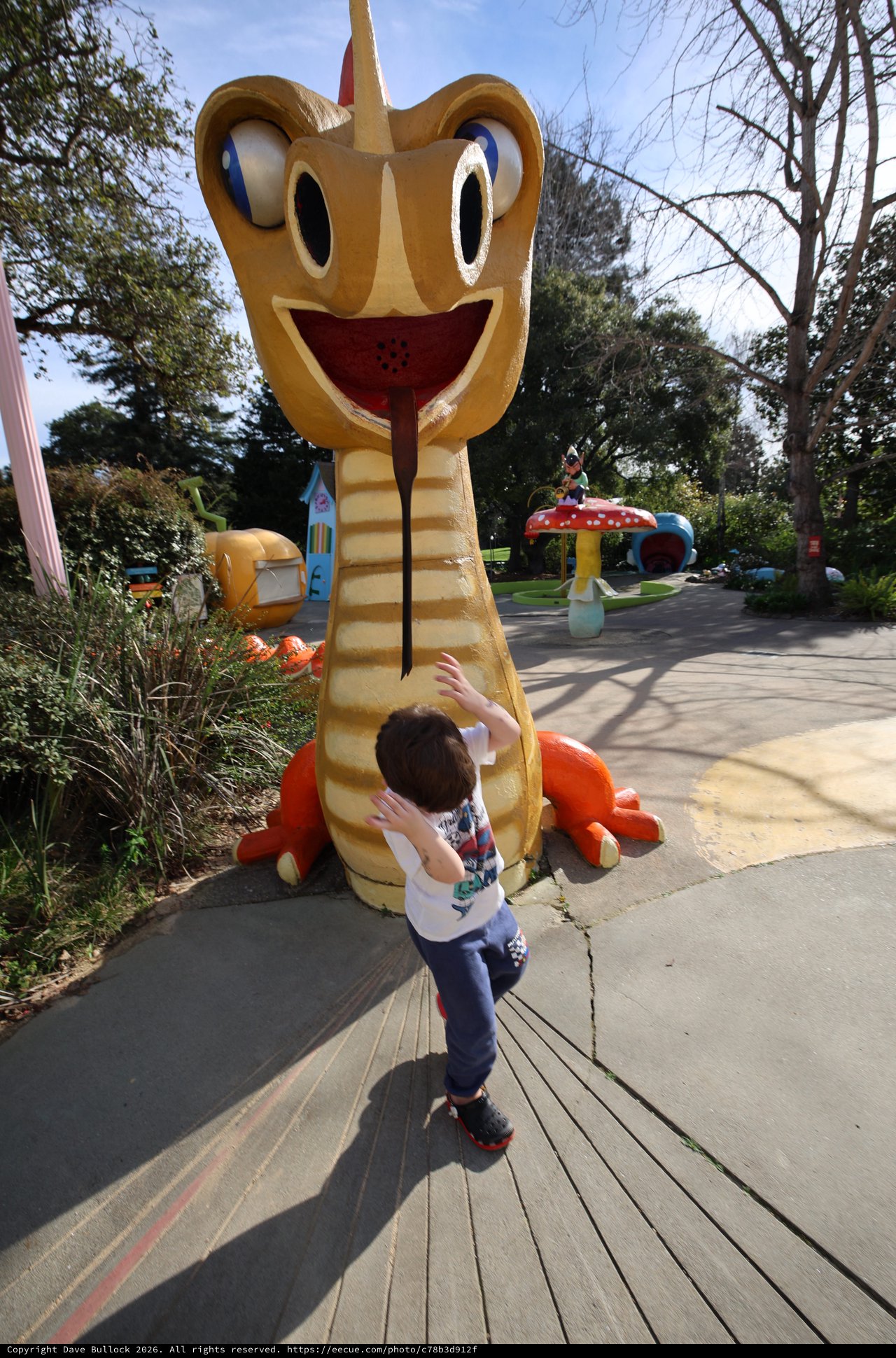Child Exploring Whimsical Snake Sculpture in Theme Park