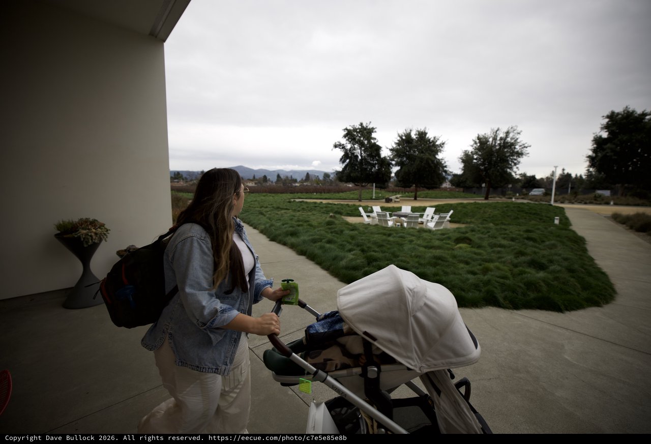 Mother with Stroller Walking Under Covered Patio at Dusk
