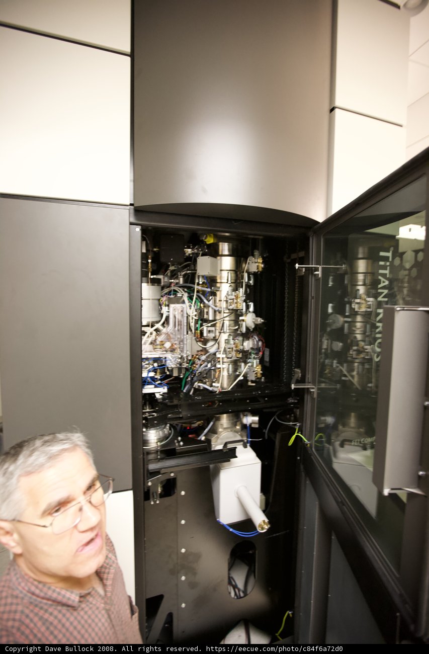 Man Examining Optical Equipment in a Technical Setting
