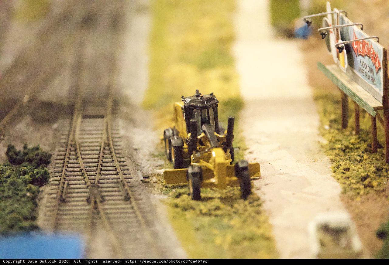 Miniature Road Grader Beside Model Railroad Tracks