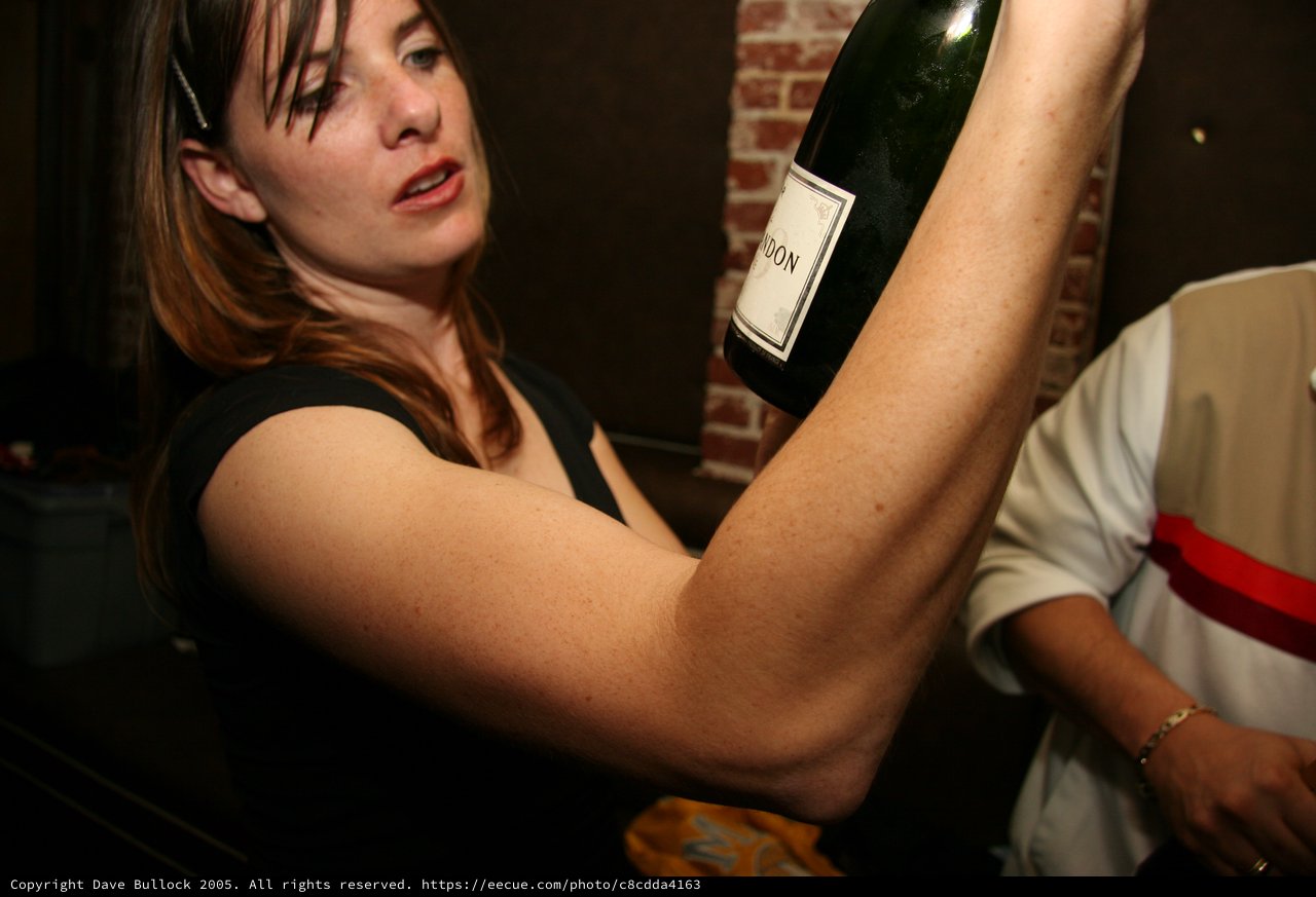 Woman Hoisting Champagne Bottle at Holiday Party