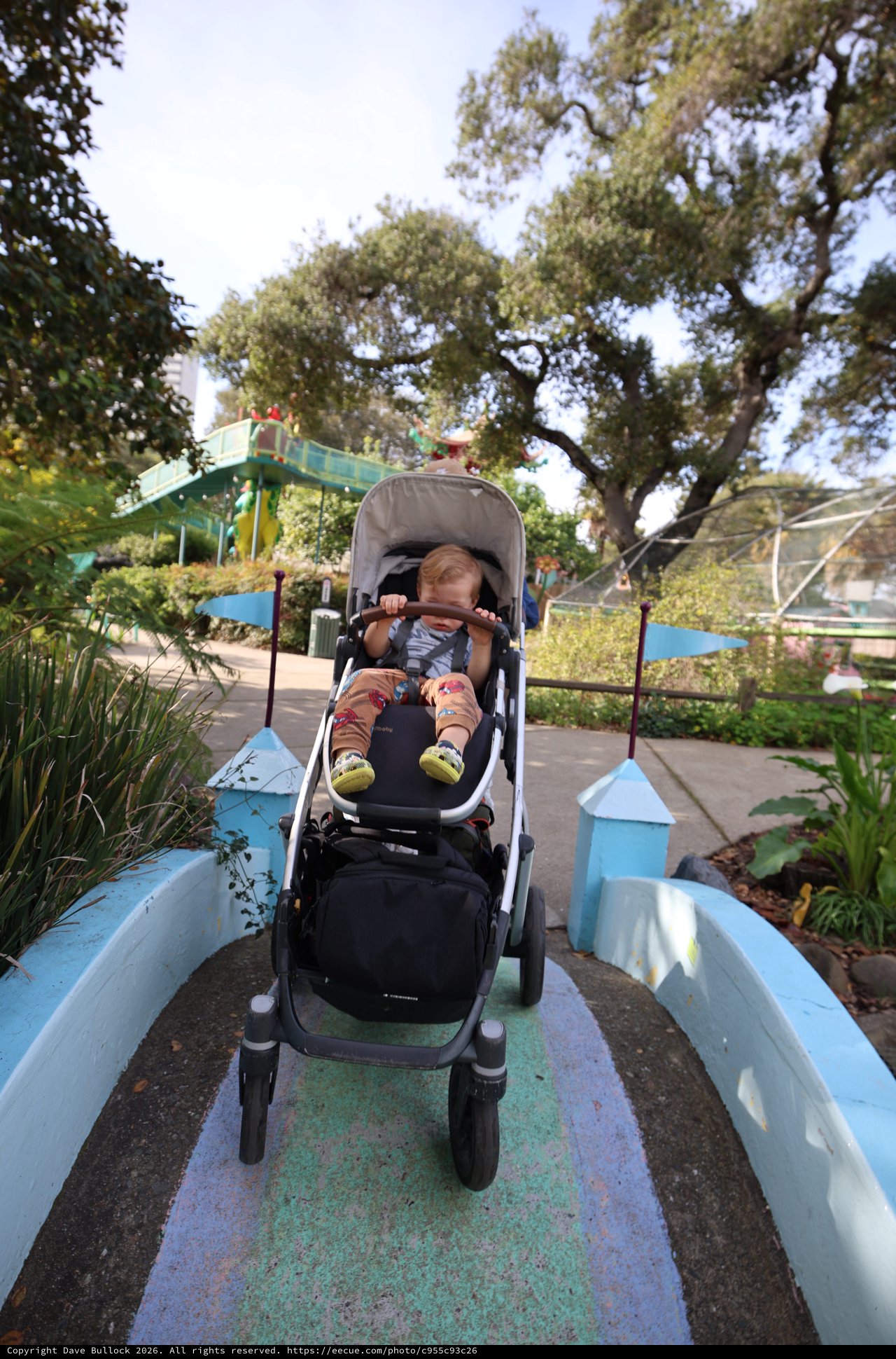 Child in Stroller on Whimsical Garden Bridge Path
