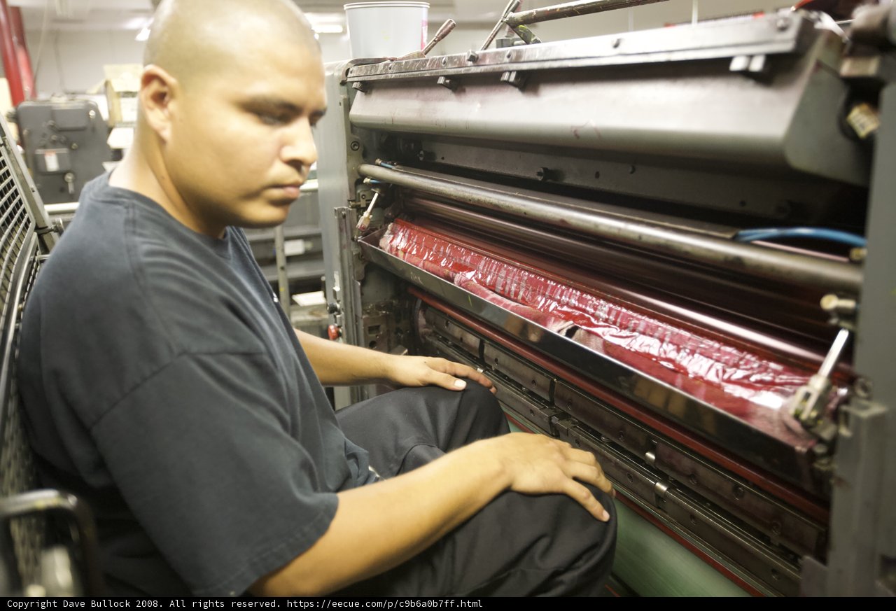Hard At Work: Man Operating Printing Machine in Factory